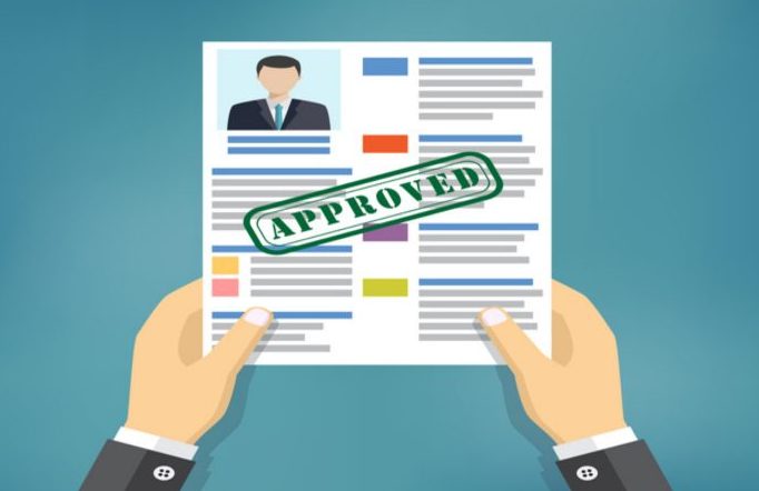 Hand holding resume with Approved stamp mark.